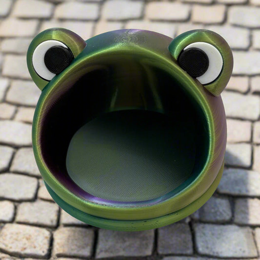 Frog-shaped container with googly eyes on a white background, featuring the 'Miniature Heroes' logo.